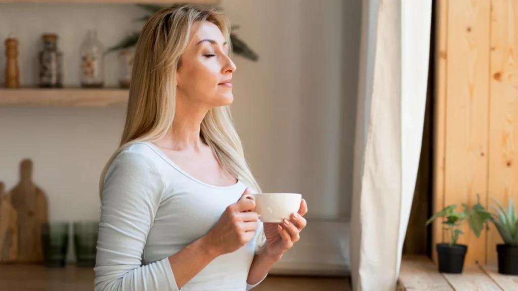 Woman in her 50s standing in calm morning light with a peaceful, settled expression after completing a sugar-free reset.