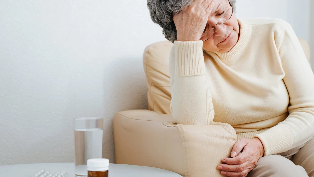 Exhausted senior woman with head in hand, showing next-day grogginess from sleeping pills after 65.