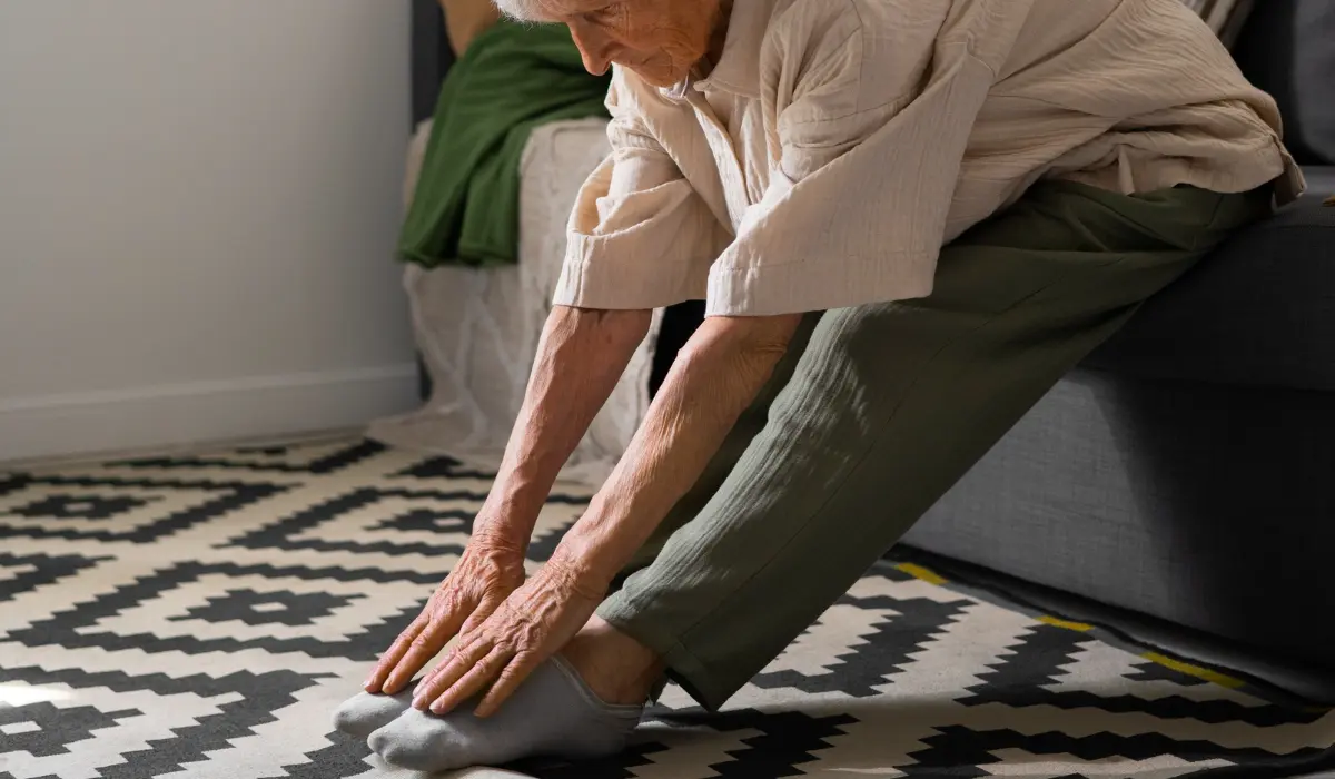 Older woman doing a leg stretch at home to ease bone aches and support joint health after 50.