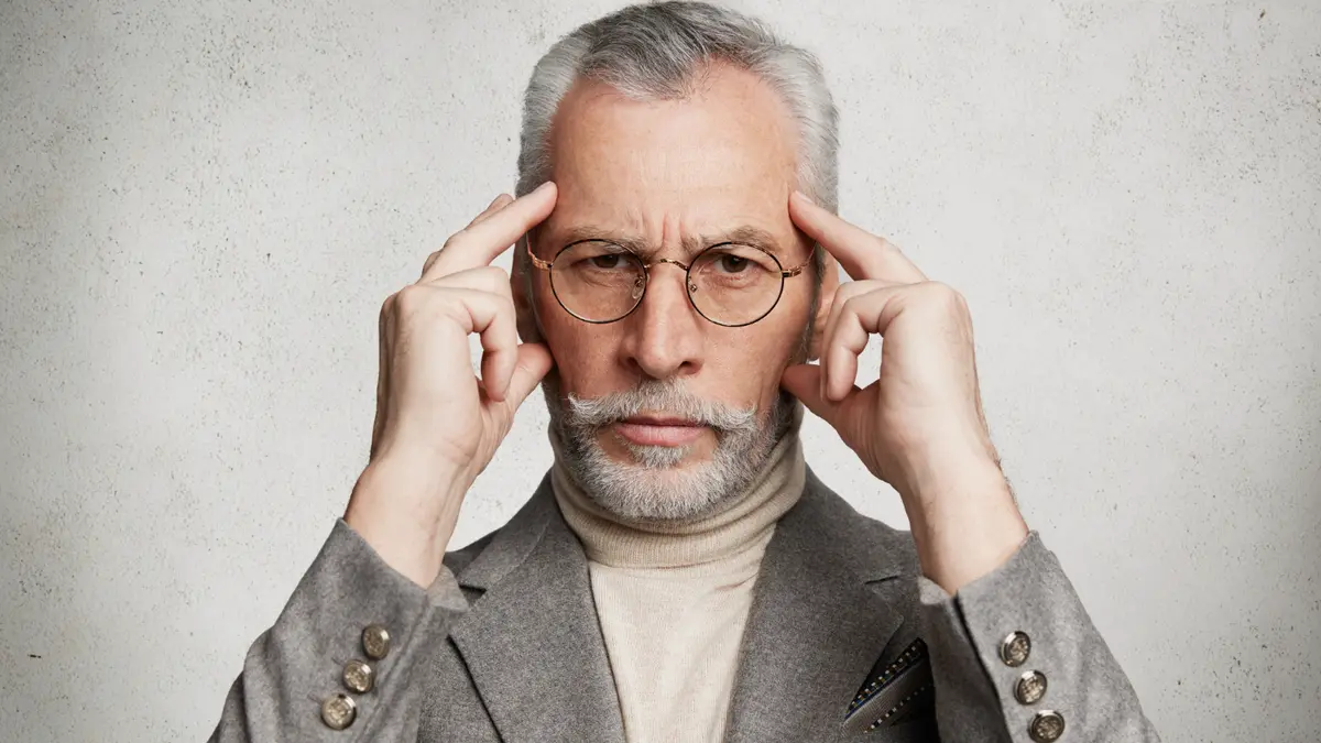 Distraught senior man with hand on temple, reflecting on how low B12 affects brain cell health