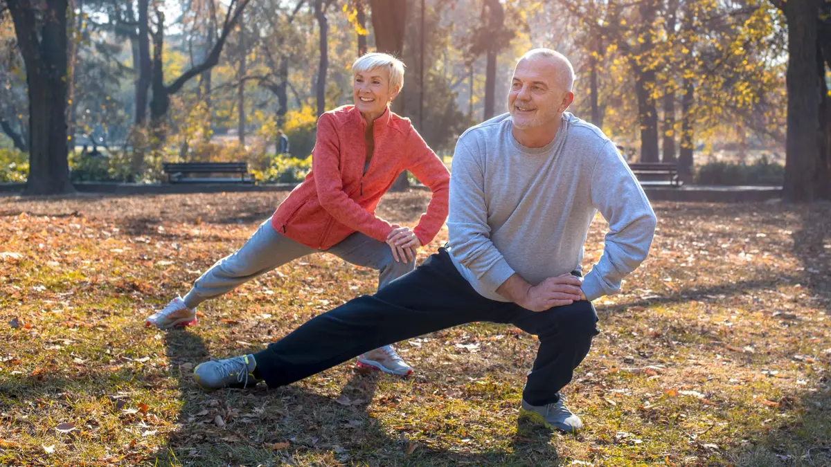 Mature couple stretching in a park to improve mobility and combat muscle stiffness after 50