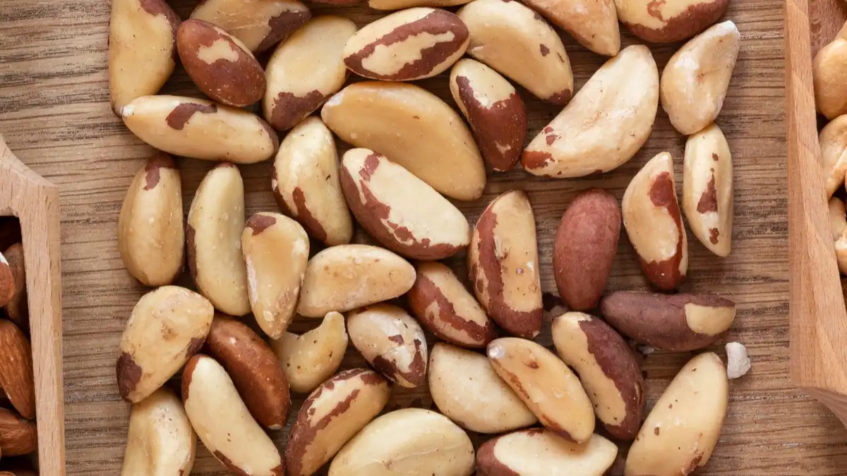 Close-up of raw Brazil nuts on a wooden surface, a rich natural source of selenium for thyroid health after 50.
