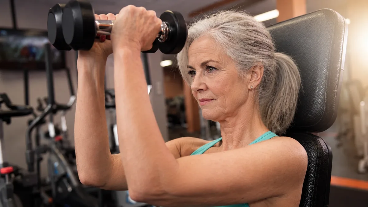 A woman lifting dumbbells during a strength training session to boost metabolism and build muscle after 40.