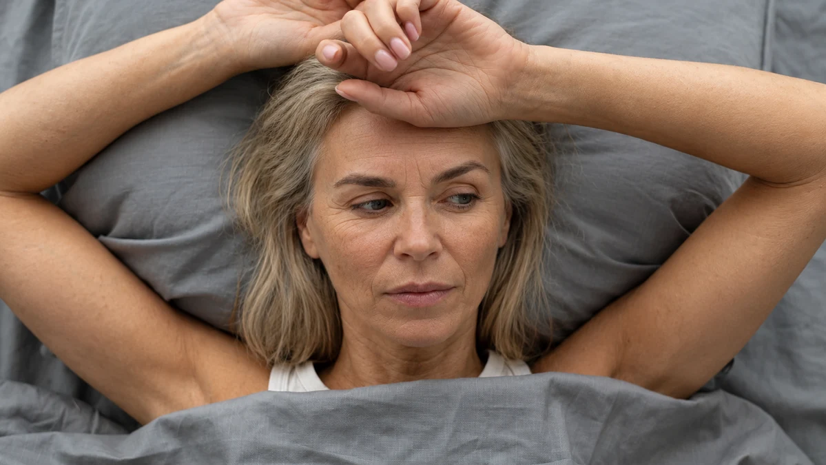 A woman lying awake in bed at night unable to sleep due to perimenopause hormone shifts disrupting her deep sleep cycle.