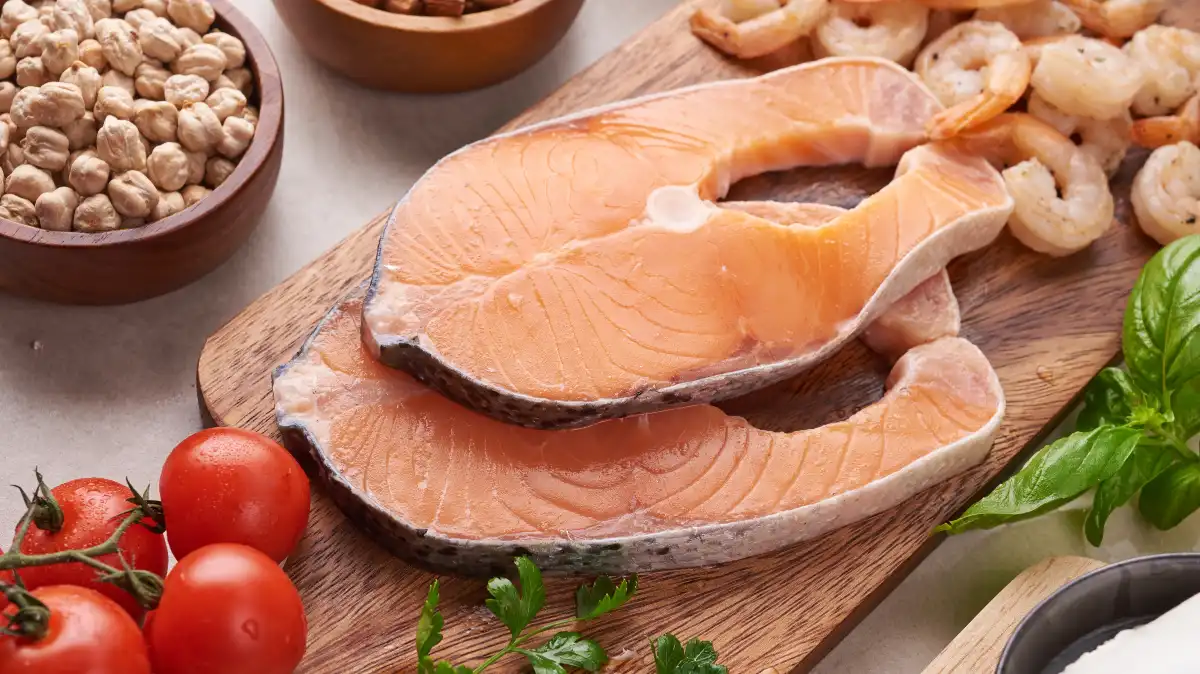 Fresh salmon fillets with shrimp and mixed vegetables on a flat surface, fatty fish providing essential vitamin D3.