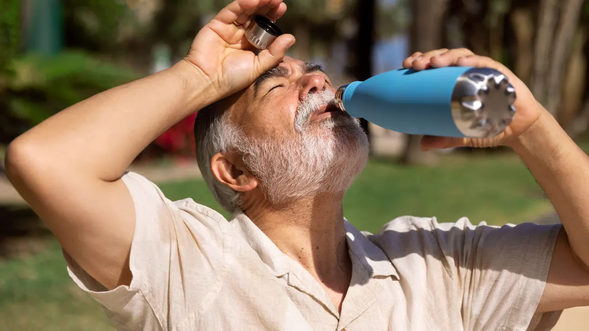 Mature man drinking fresh glass of water to keep blood thin and prevent arterial stiffness from dehydration.