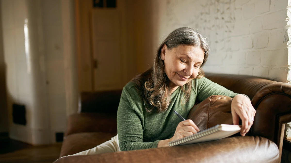 A woman in her 60s writes in a journal to track improvements in her skin elasticity and nail strength