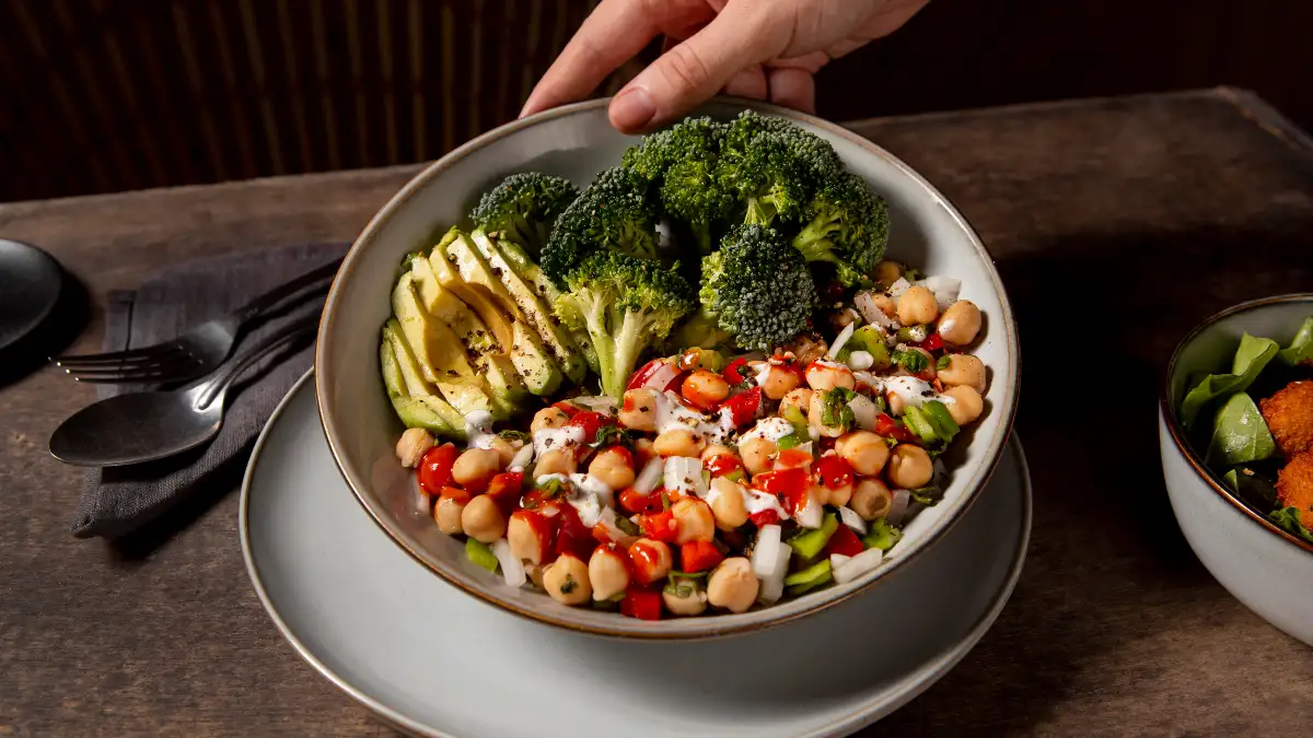 Bowl of broccoli and chickpeas placed on a table, highlighting nutrient-rich foods for bone health support.