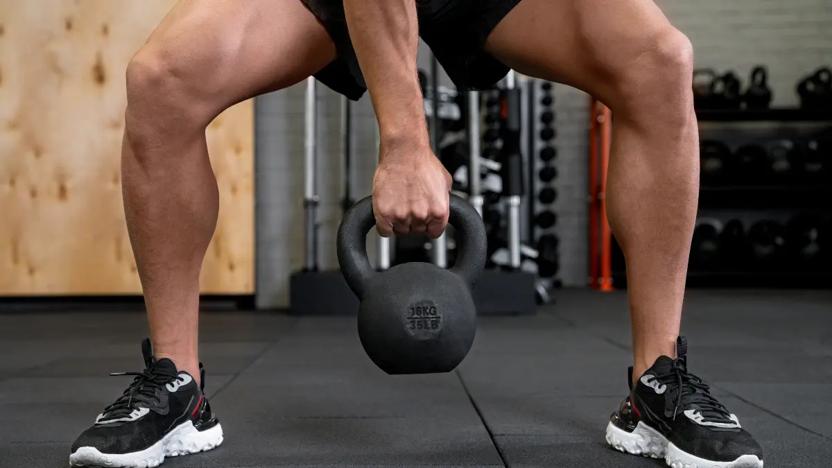 Man over 50 performing Farmer's Carry with heavy kettlebells to build muscle mass and support heart health