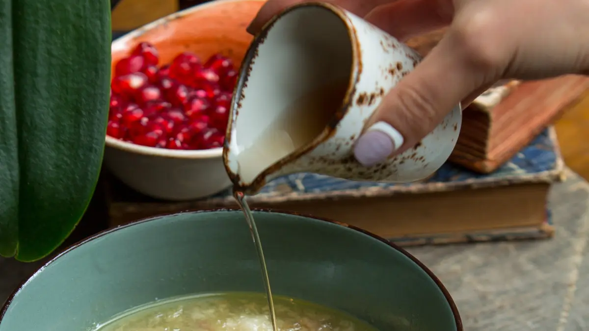 Pouring collagen-rich bone broth into a bowl of soup to strengthen the gut lining and manage nightshade-triggered inflammation after 50