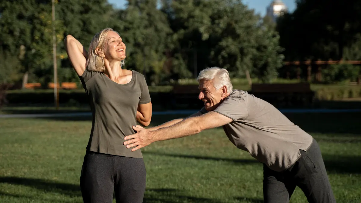 Mature couple stretching on a sunlit patio to improve mobility and combat muscle stiffness after 50