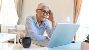 Mature woman experiencing fight or flight after 50 while working at a laptop in her home office