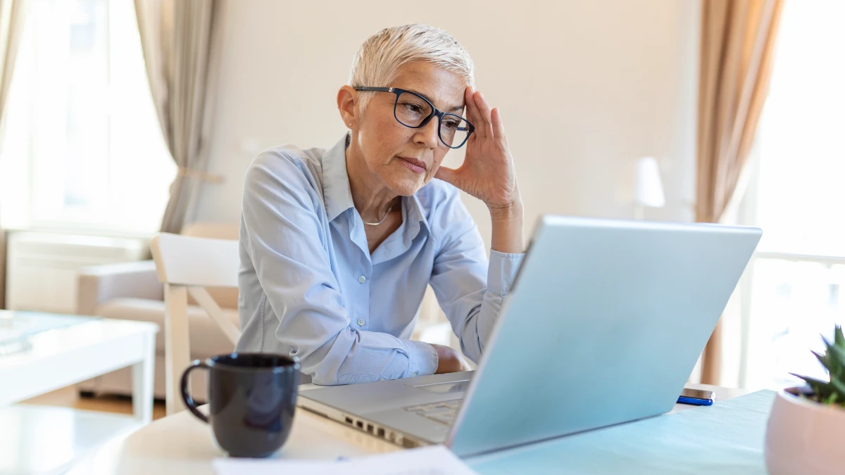 Mature woman experiencing fight or flight after 50 while working at a laptop in her home office
