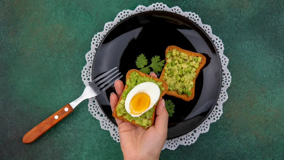 Avocado and eggs on whole grain toast, healthy fat breakfast to support hormone balance.
