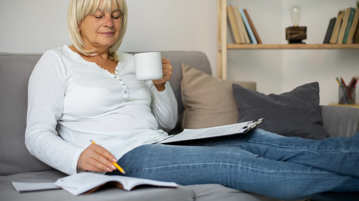 Senior woman recording daily joint stiffness in a journal to track patterns and facilitate effective cortisol management