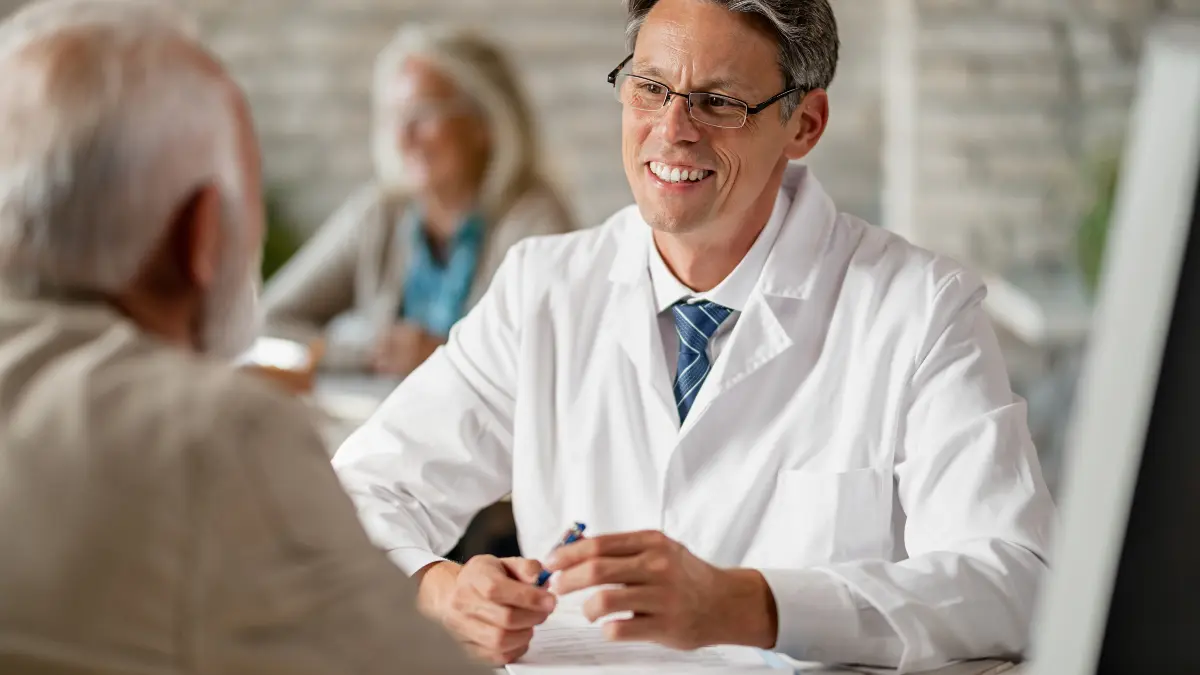 A mature man discusses options with an audiologist in a bright, modern office to improve his hearing health