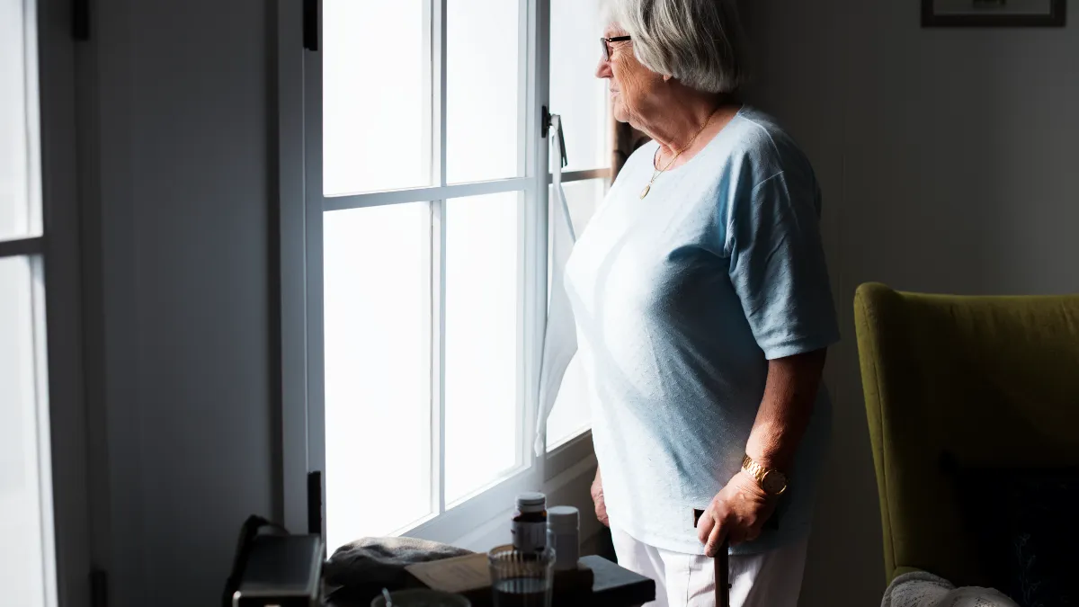Senior woman in her 60s sitting by a window at home, thoughtfully considering her kidney health and dietary changes after 50