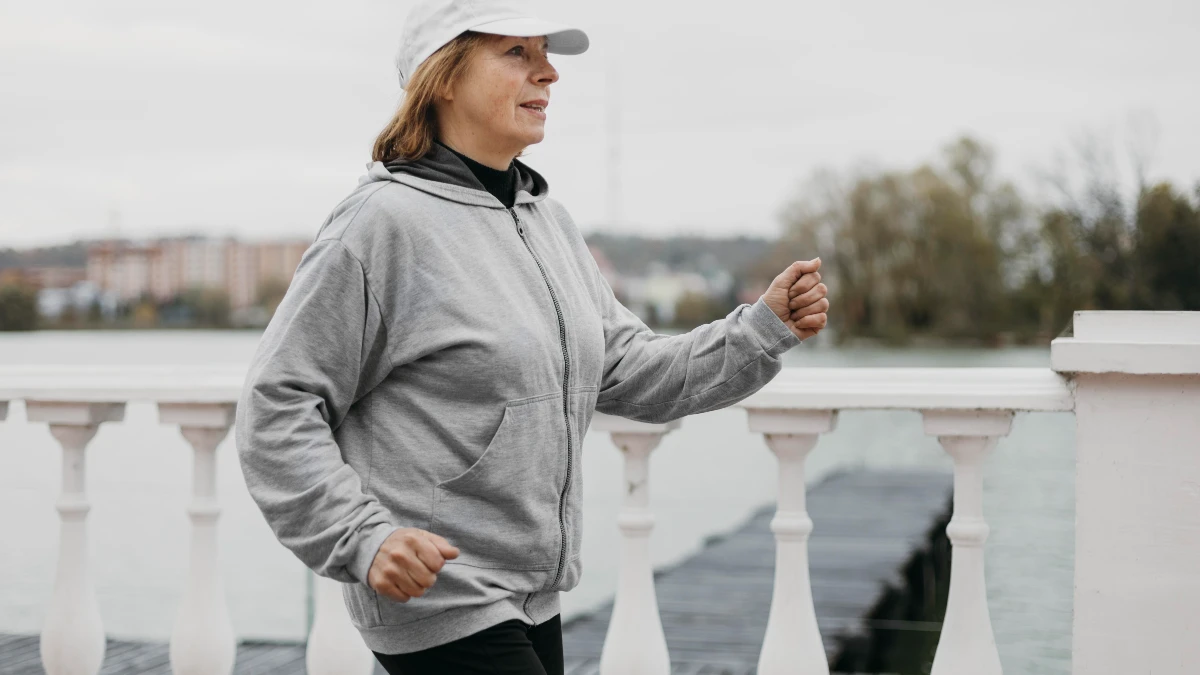 A mature woman walks through a sunlit park to lower cortisol levels and support her hormonal balance.