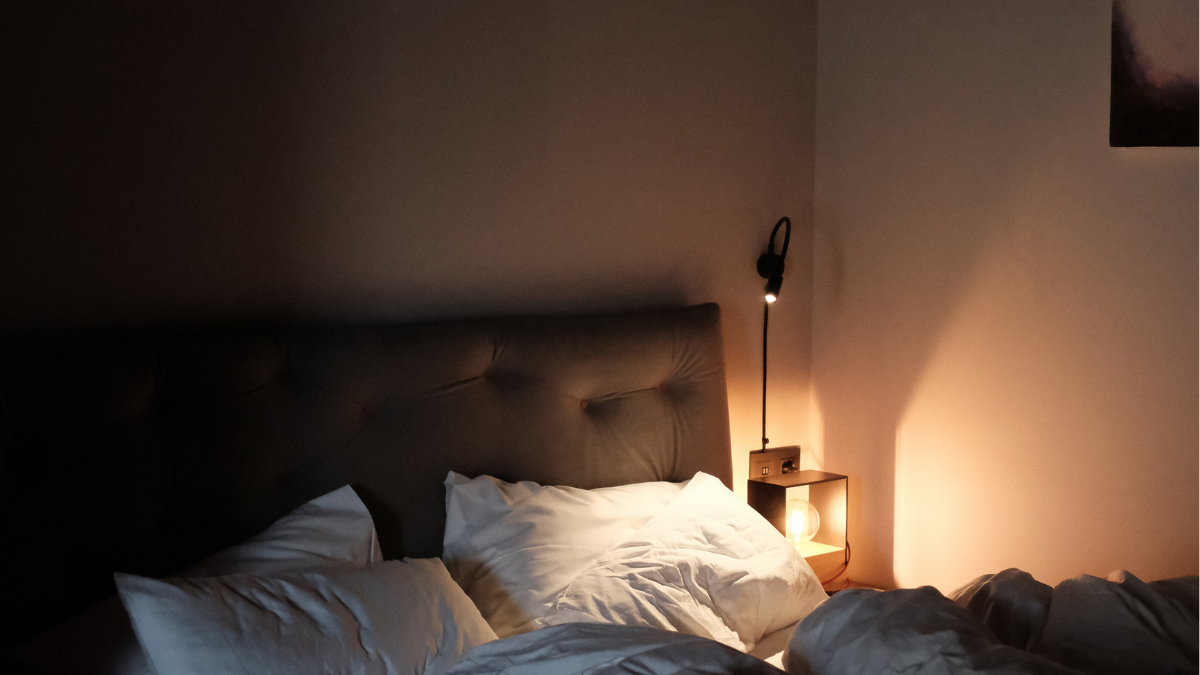 Serene bedroom with warm yellow bedside lamp and made bed, ideal environment for 4 7 8 breathing protocol