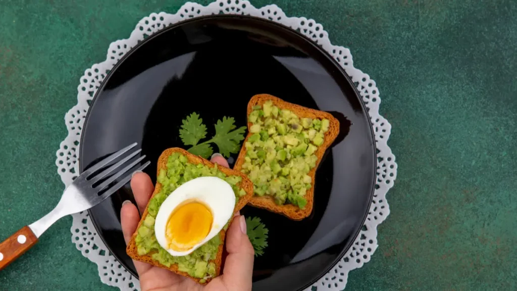 Sliced avocado and soft-boiled eggs stimulating absorption of fat-soluble vitamins like K2.
