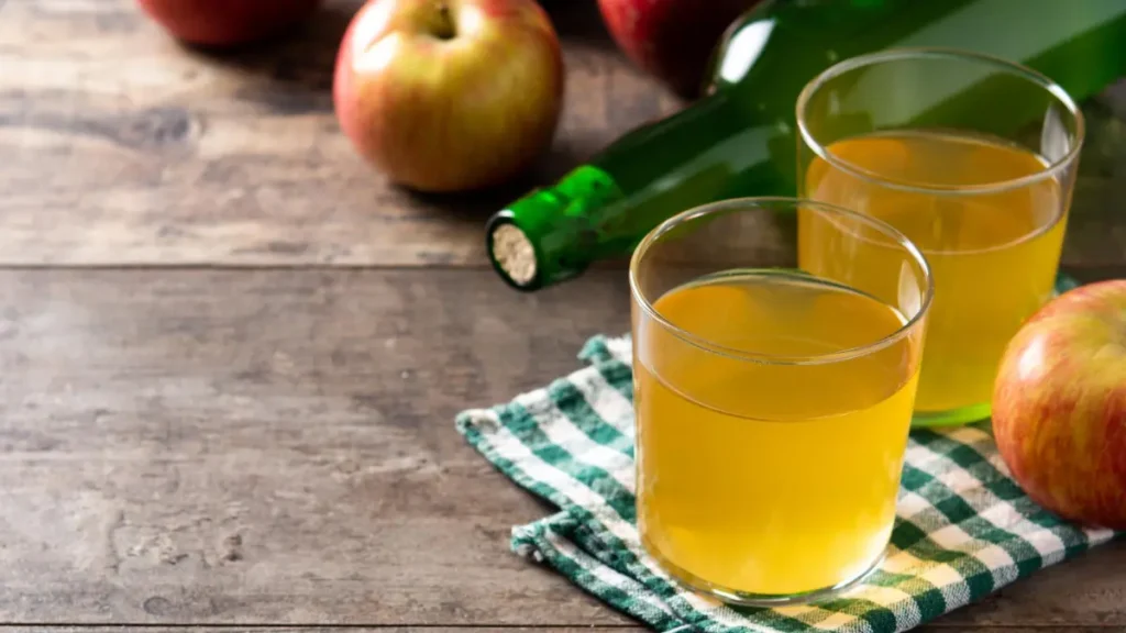 Two glasses of diluted apple cider vinegar on a wooden table to stimulate stomach acid and support metabolic heat production before meals.