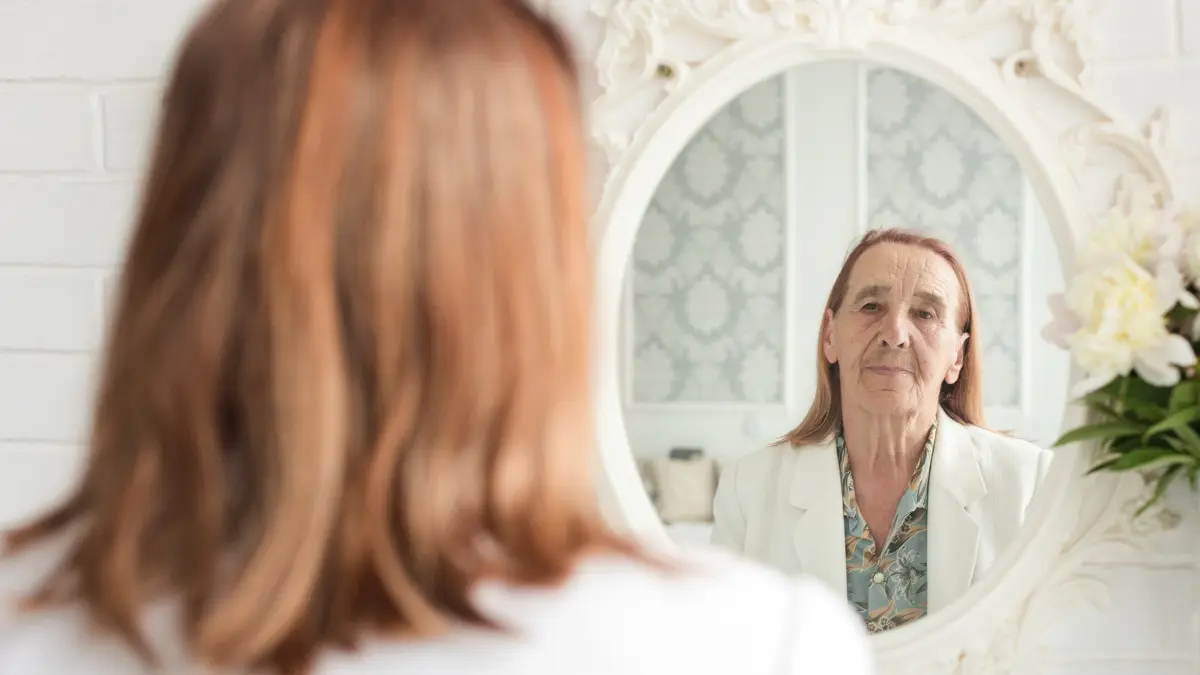 Mature woman looking in a mirror to identify an earlobe crease high blood pressure signal.