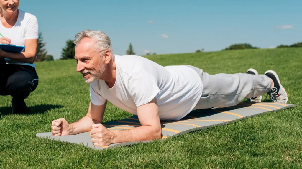 Mature man exhaling during a plank hold to maintain steady cortisol management while exercising.