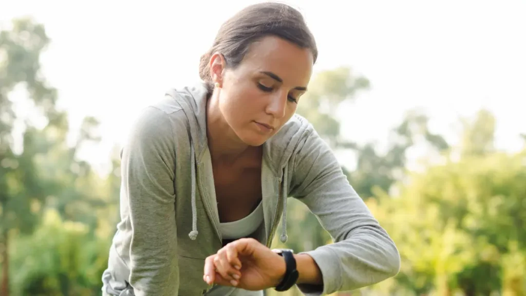 Woman checking her fitness tracker during a morning walk to balance cortisol management.