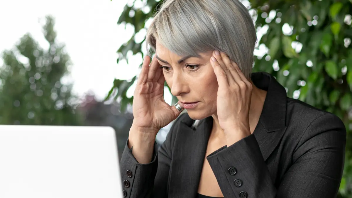 Mature woman experiencing afternoon brain fog while working at her computer to manage cortisol management.
