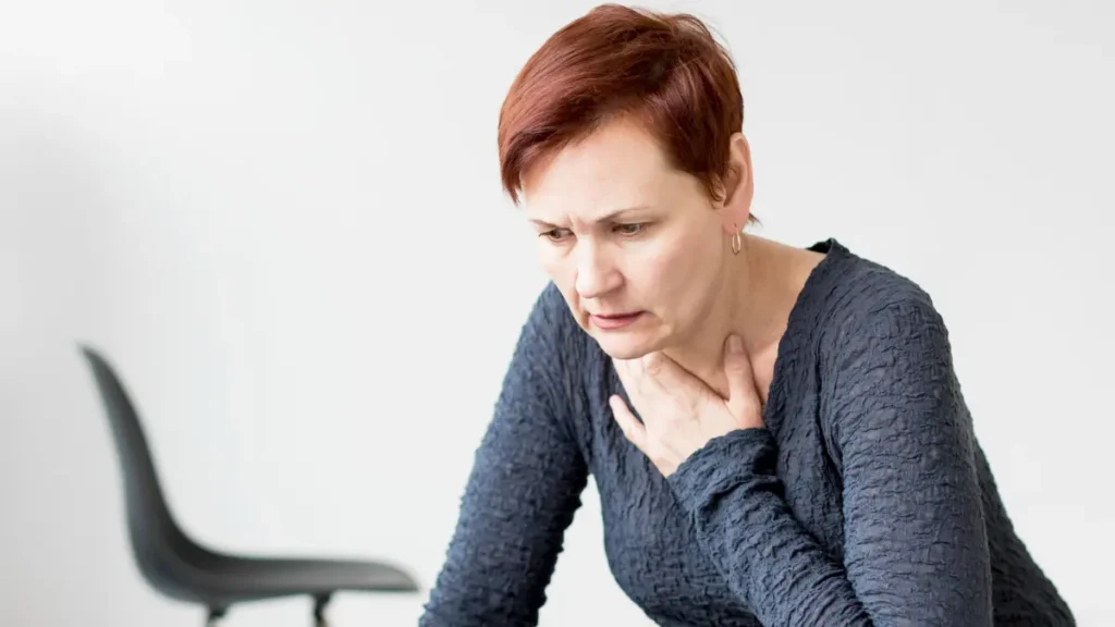 Mature woman experiencing chest pressure and discomfort often mistaken for high acid while managing low stomach acid symptoms.