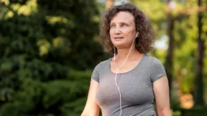 Focused mature woman walking briskly outdoors to stimulate metabolic heat production and brain health.