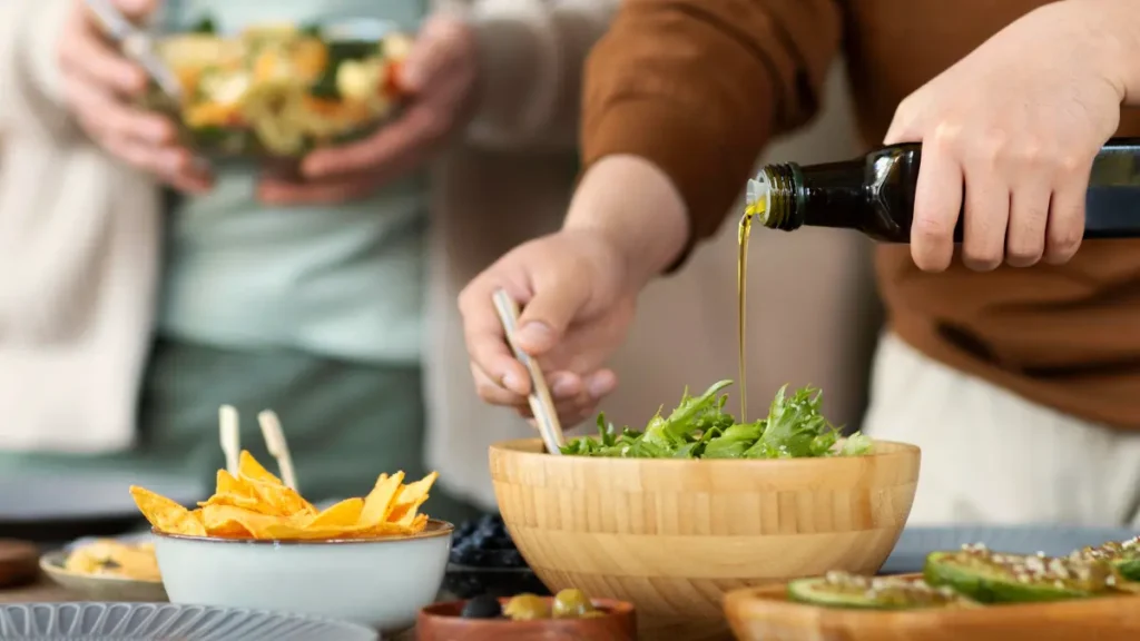 Drizzling olive oil over bitter greens to trigger a gentle contraction for cortisol management and healthy bile release.