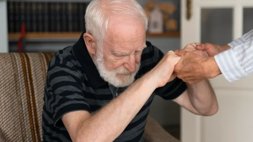 Senior man hesitating to stand from a chair due to age-related sarcopenia.