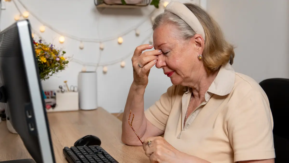 Mature working woman at a desk rubbing her eyes to combat an energy crash after eating lunch.