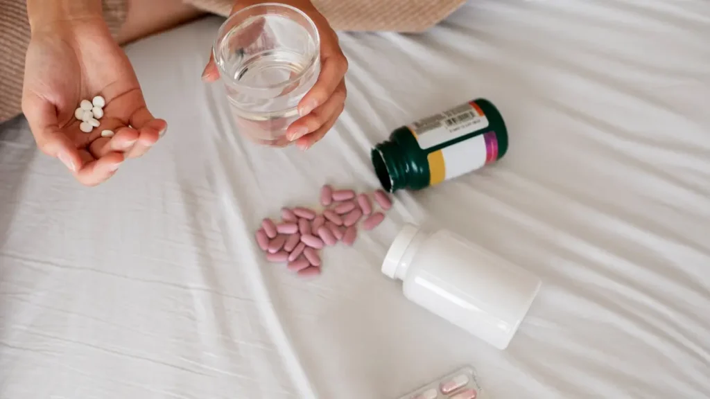 Overhead view of hands with water and pills to show how sleep aids can stall glymphatic system waste clearance.