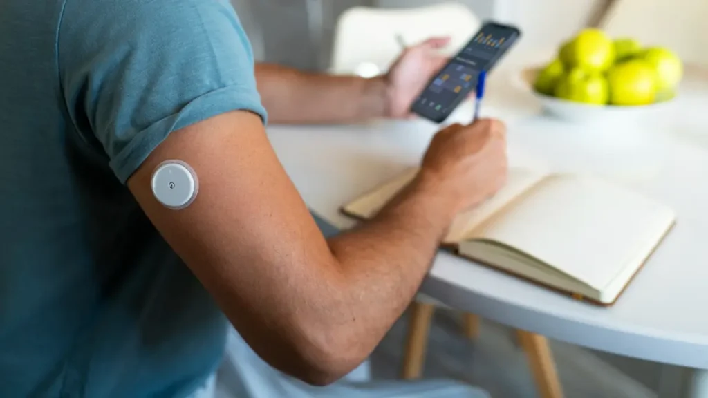 Adult using a continuous glucose monitor and smartphone app to track blood sugar patterns and metabolic responses.