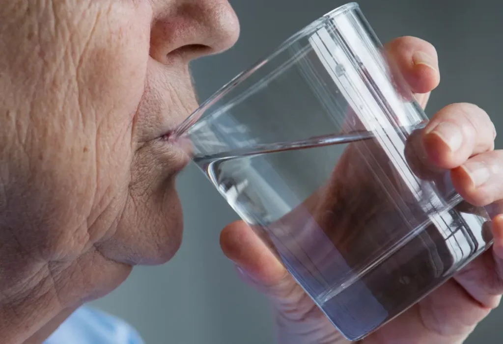 Mature woman drinking water to improve magnesium absorption and support basal metabolic rate.