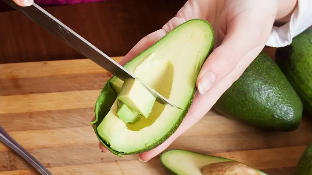 Hands slicing a fresh avocado to include potassium-rich foods for supporting electrolyte balance.