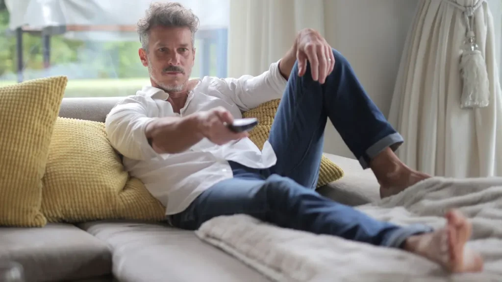 Mature man reclining on a sofa to demonstrate cortisol management and nervous system relaxation.
