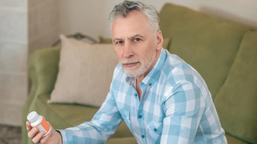 Mature man comparing supplement bottles to select magnesium glycinate for restoring cellular energy.