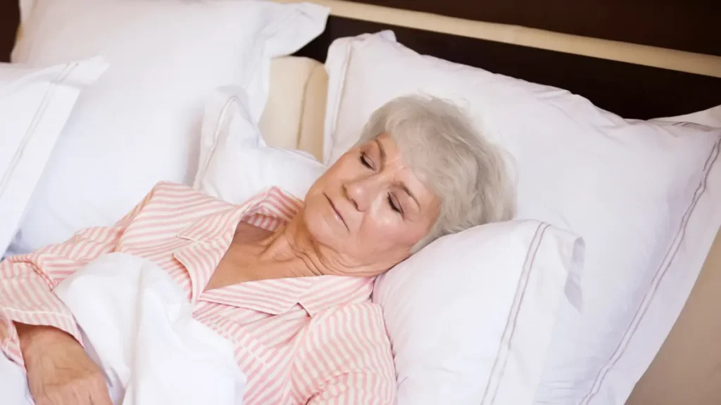 Mature woman sleeping with elevated pillows to manage orthostatic hypotension and overnight fluid volume.