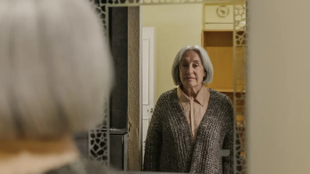 Mature woman checking her posture in a mirror to identify early signs of bone loss.