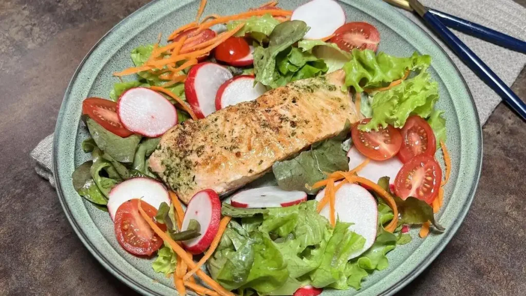 Herb-crusted salmon fillet on a bed of fresh greens to support metabolic heat production and prevent evening food sits heavy after eating sensations.