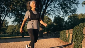 Mature woman walking outdoors in a weighted vest to improve bone density after 50.
