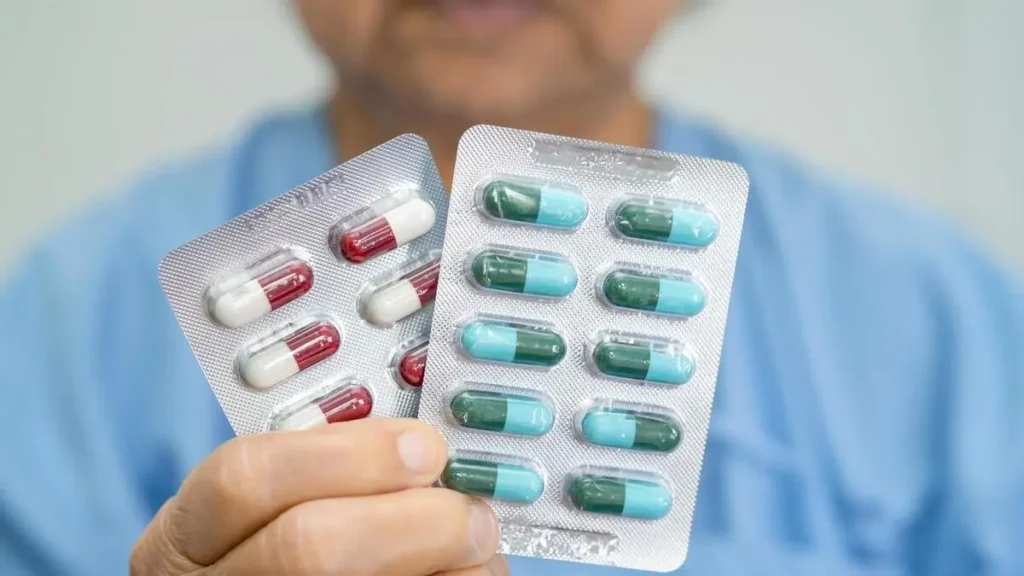 Woman holding a handful of capsules and water while considering vitamins for over 50 and supplement absorption.