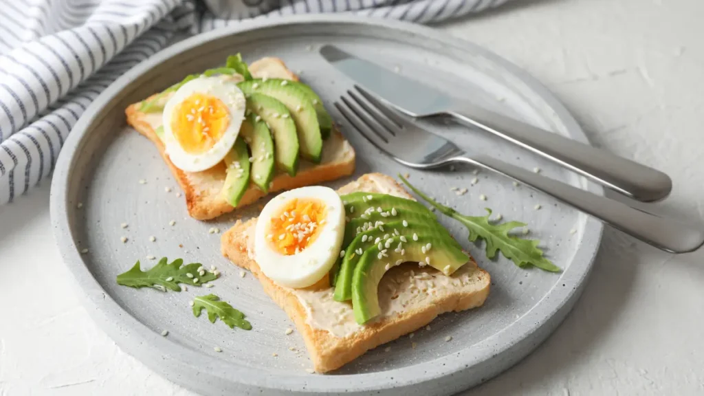 Sliced avocado and soft-boiled eggs on toast to trigger metabolic heat production for fat-soluble vitamin absorption.