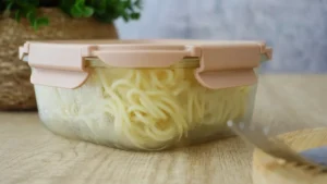 Cooked pasta stored in a sealed glass container on a wooden surface, ready to chill overnight for resistant starch gut health benefits.