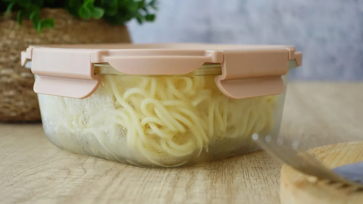 Cooked pasta stored in a sealed glass container on a wooden surface, ready to chill overnight for resistant starch gut health benefits.