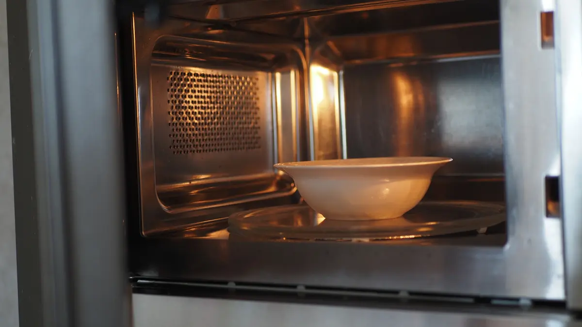 White bowl reheating in a clean microwave oven, the method shown to lower blood sugar spikes by 50 percent in pasta meals.