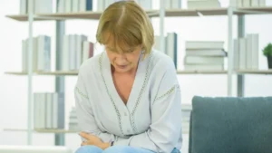 Mature woman resting her hand on her abdomen to manage food sits heavy after eating sensations during a meal.